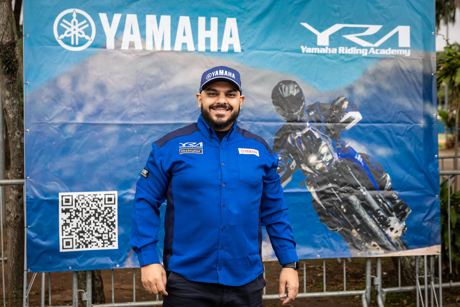 Geraldo Ramos, instrutor de pilotagem certificado, em frente ao banner da Yamaha Riding Academy
